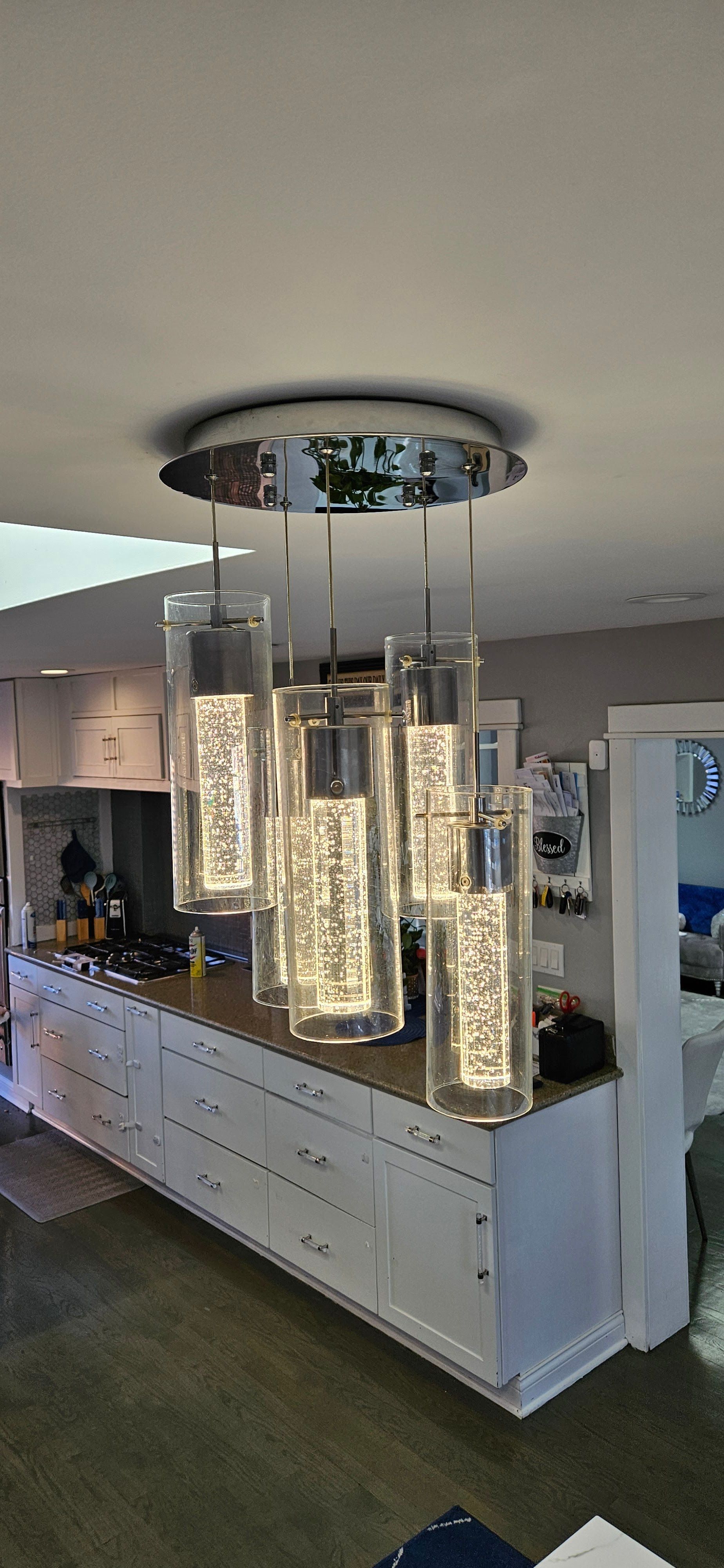 Modern dining room with a hanging chandelier over a long white buffet cabinet