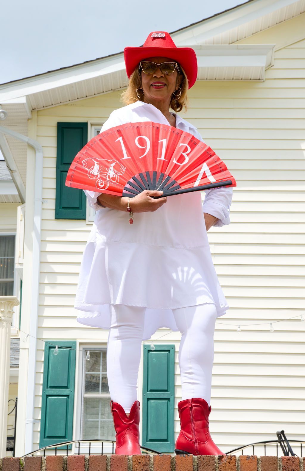Woman in red hat and boots holding a red fan with 