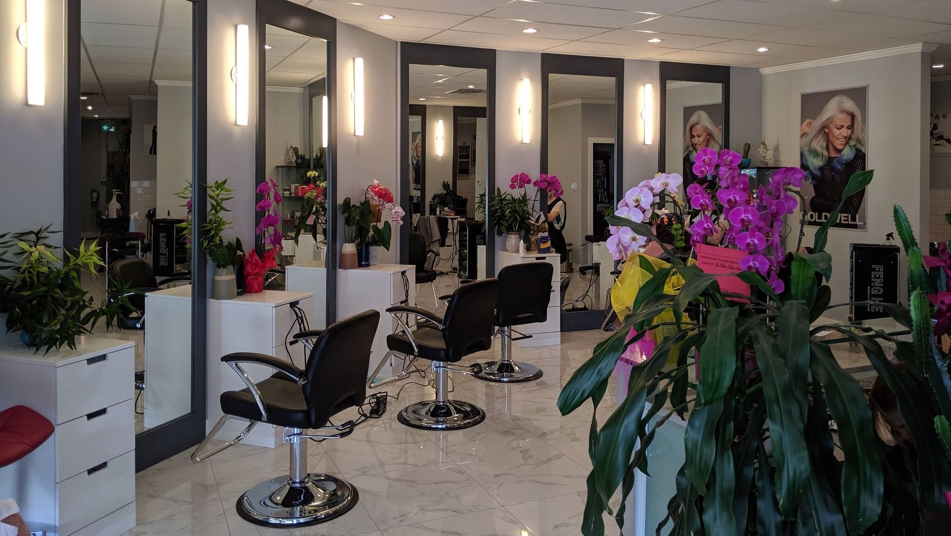 Hair salon interior with mirrors, chairs, and floral arrangements.