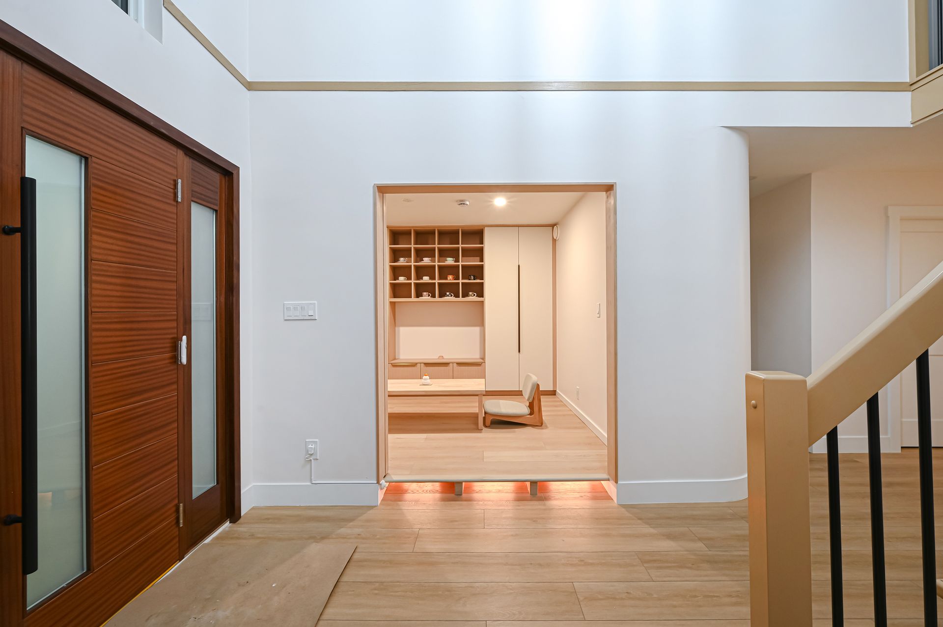Wooden entryway with door and view into a light-filled room with wood accents.
