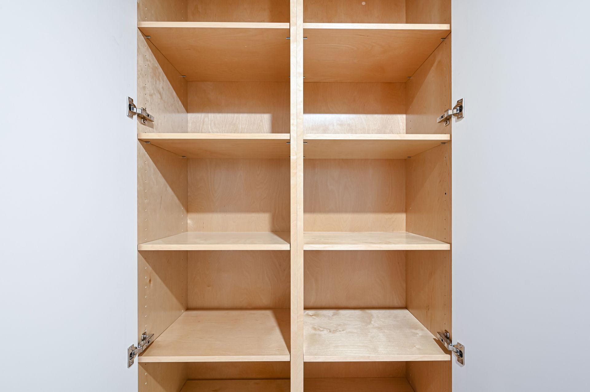 Empty wooden cabinet with multiple shelves, open against a white wall.
