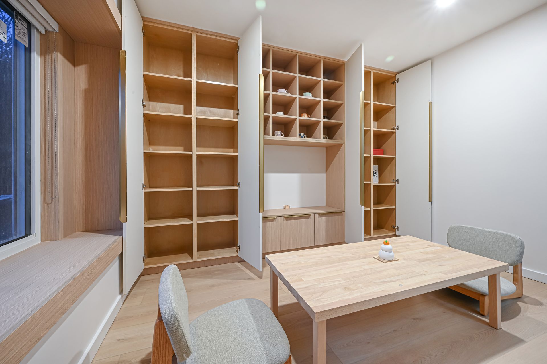 A light-filled room with built-in wooden shelves, a table, and chairs.