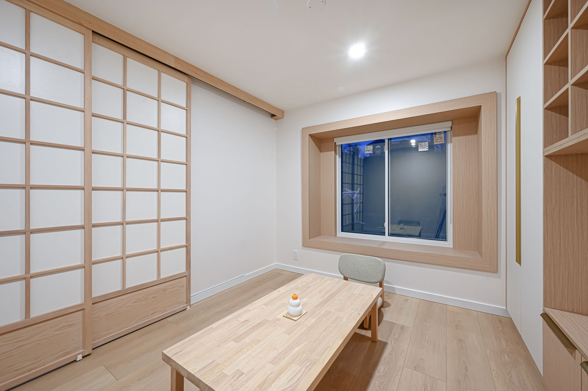 A small room with a wooden table, shoji screen doors, and a window.