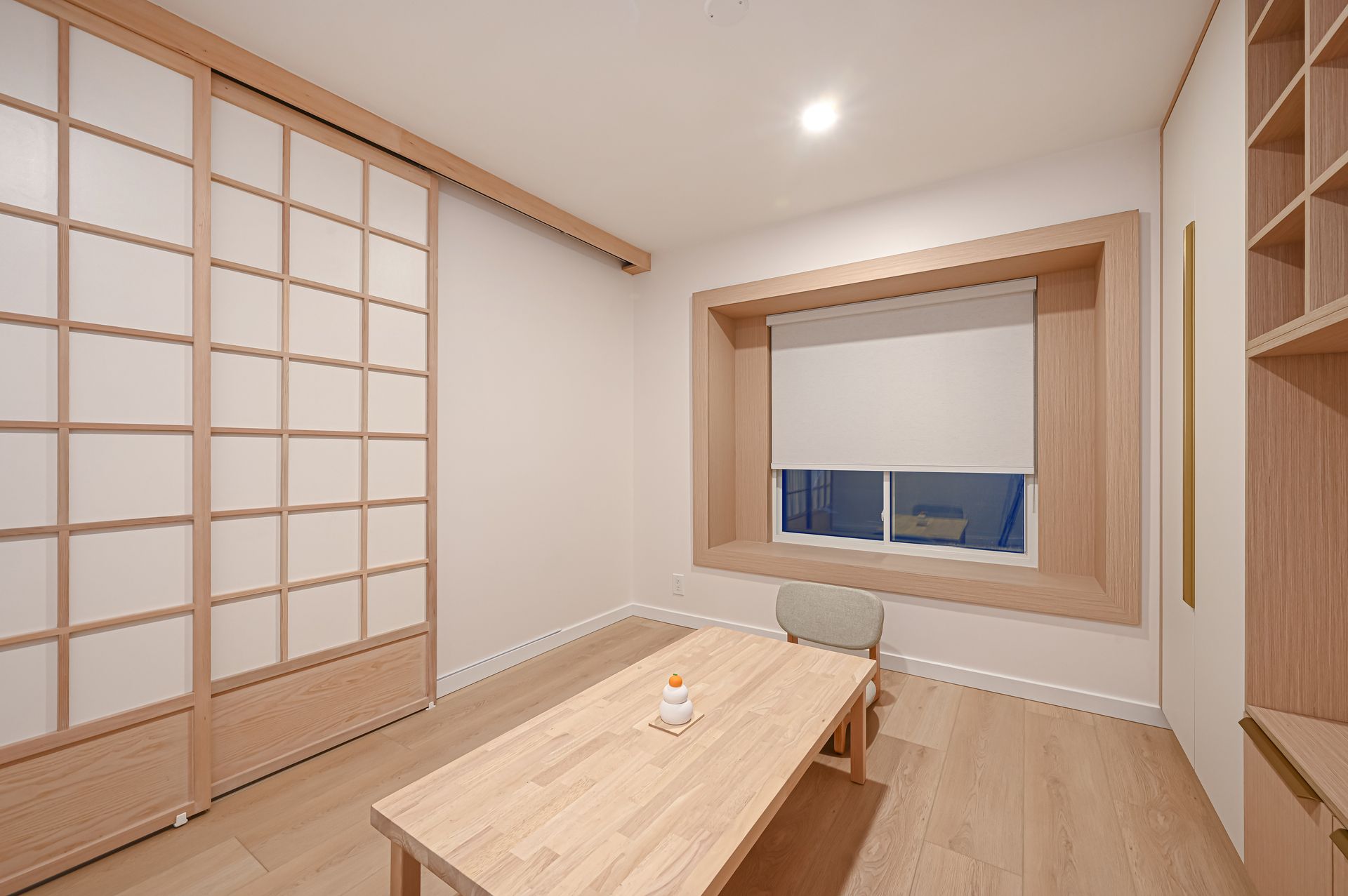 Japanese-style room: sliding shoji screen, low wooden table, built-in shelving, window with blind.