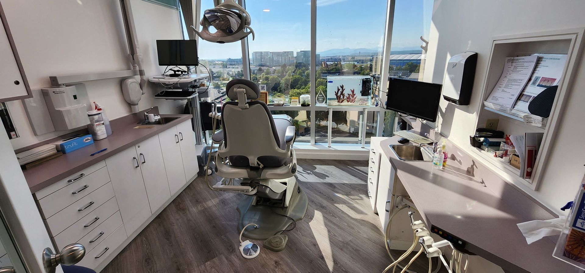 A dental office with large windows overlooking a city, a dental chair, and equipment.