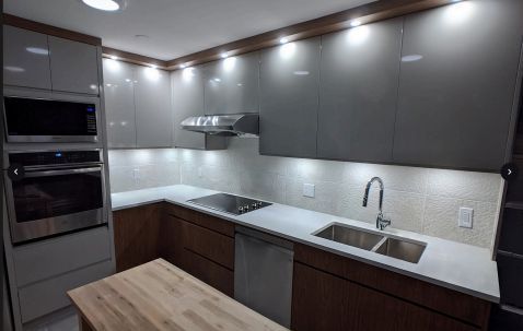 Modern kitchen with gray and brown cabinets, stainless steel appliances, and white countertop.