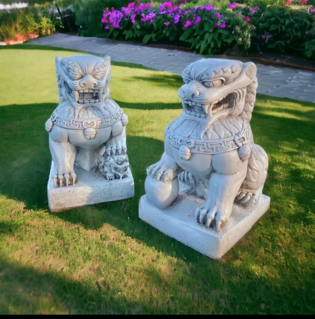 Un par de estatuas sentadas sobre un exuberante campo verde.