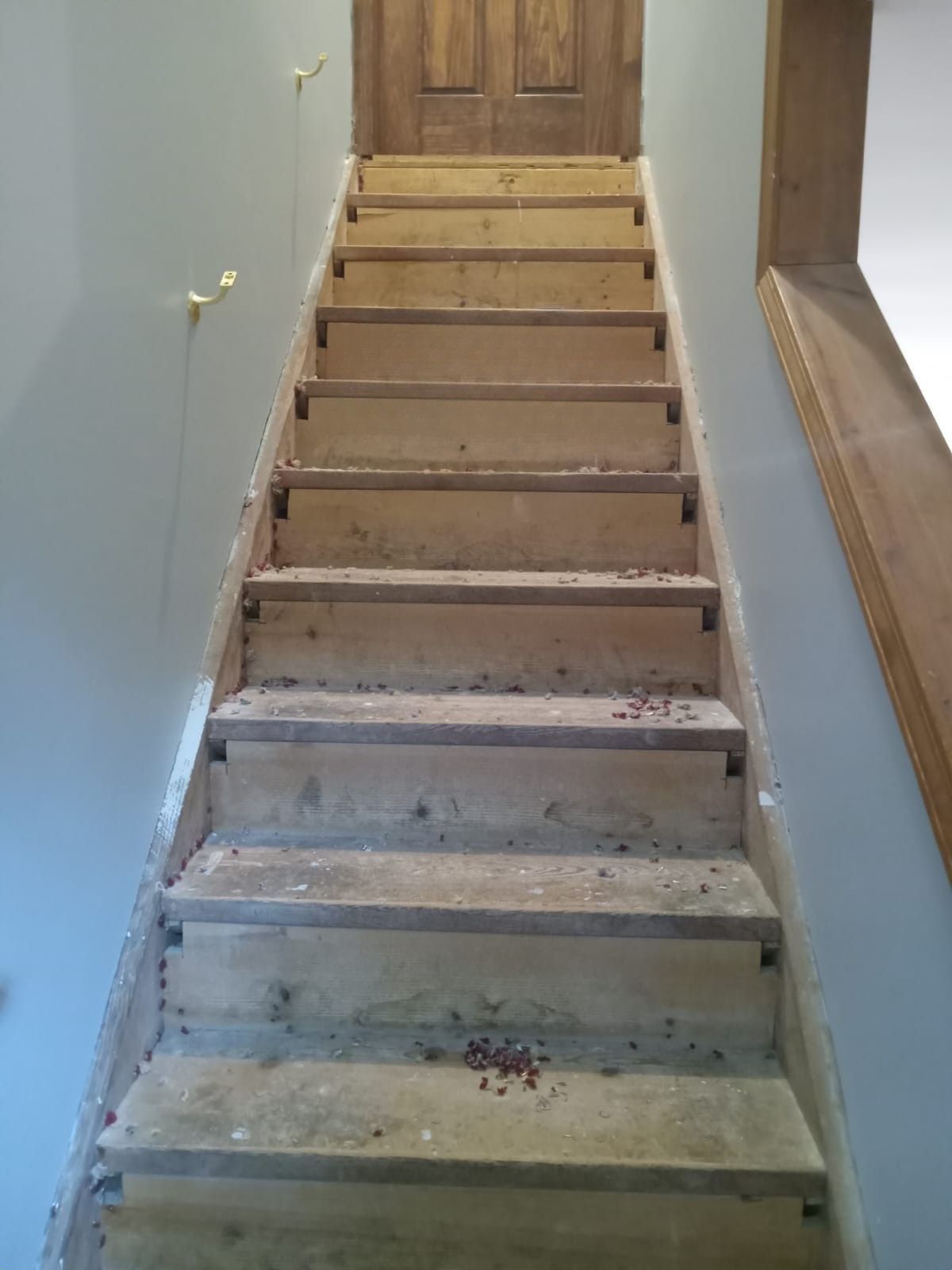 Narrow indoor staircase with unfinished concrete steps leading to a wooden door
