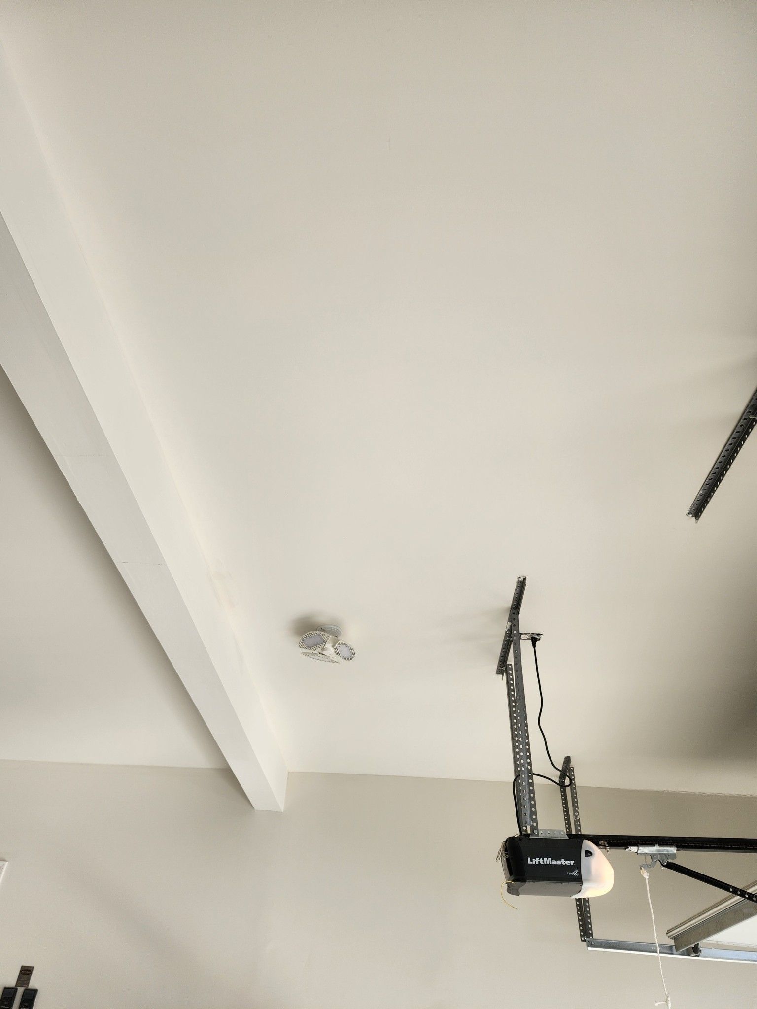 Ceiling with exposed garage door opener rail and white beams in a garage interior