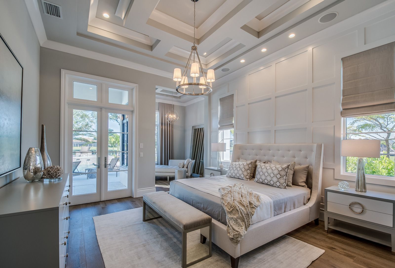 Elegant bedroom with tufted bed, chandelier, tall windows, and soft neutral decor
