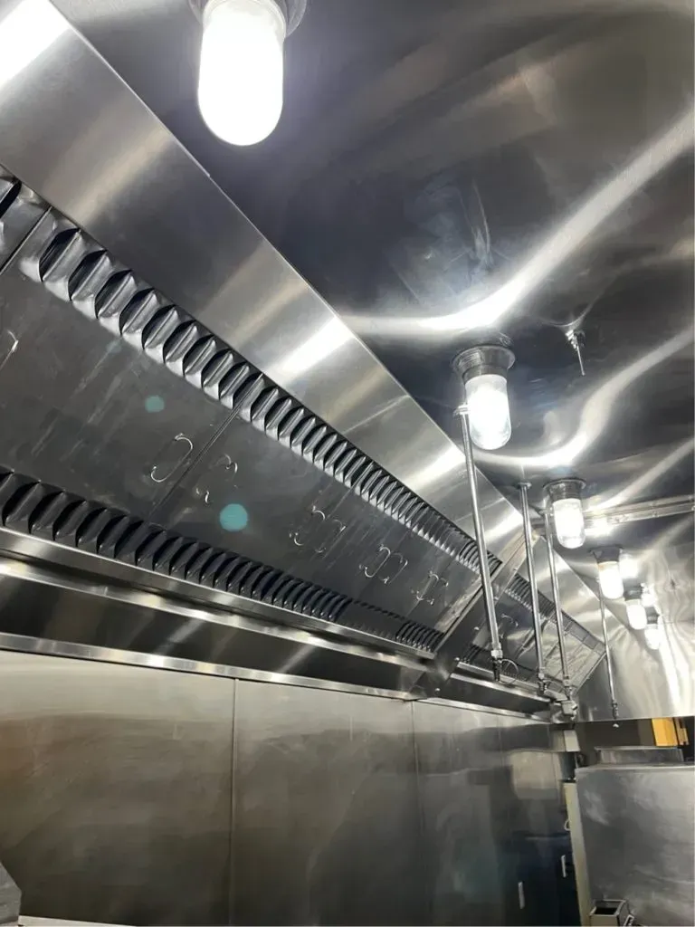 Stainless steel kitchen interior with ventilation hood and overhead lights