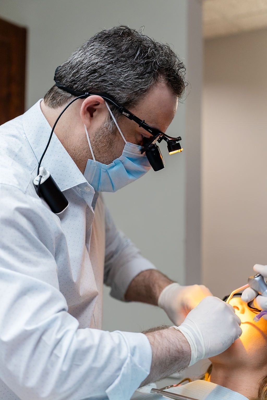 Dentist wearing a mask and magnifier working on a patient’s teeth in a clinic