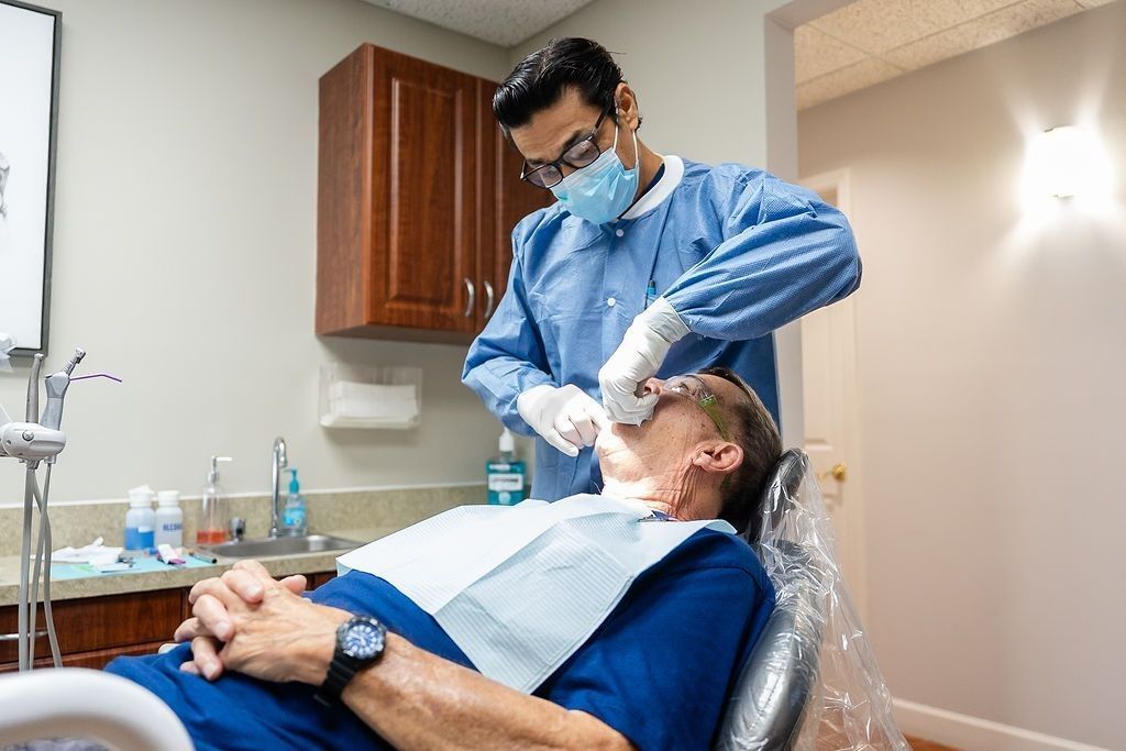 Dentist in mask and blue gloves examining a patient reclined