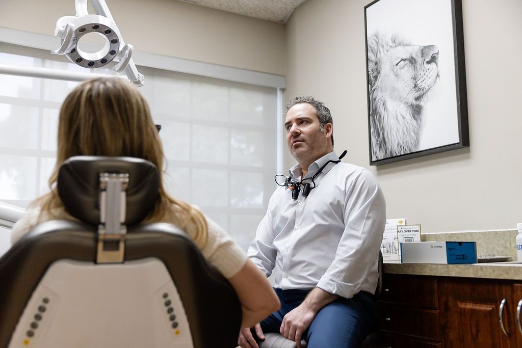 Doctor consulting with a patient in an exam room, with an eye chart and medical equipment nearby.