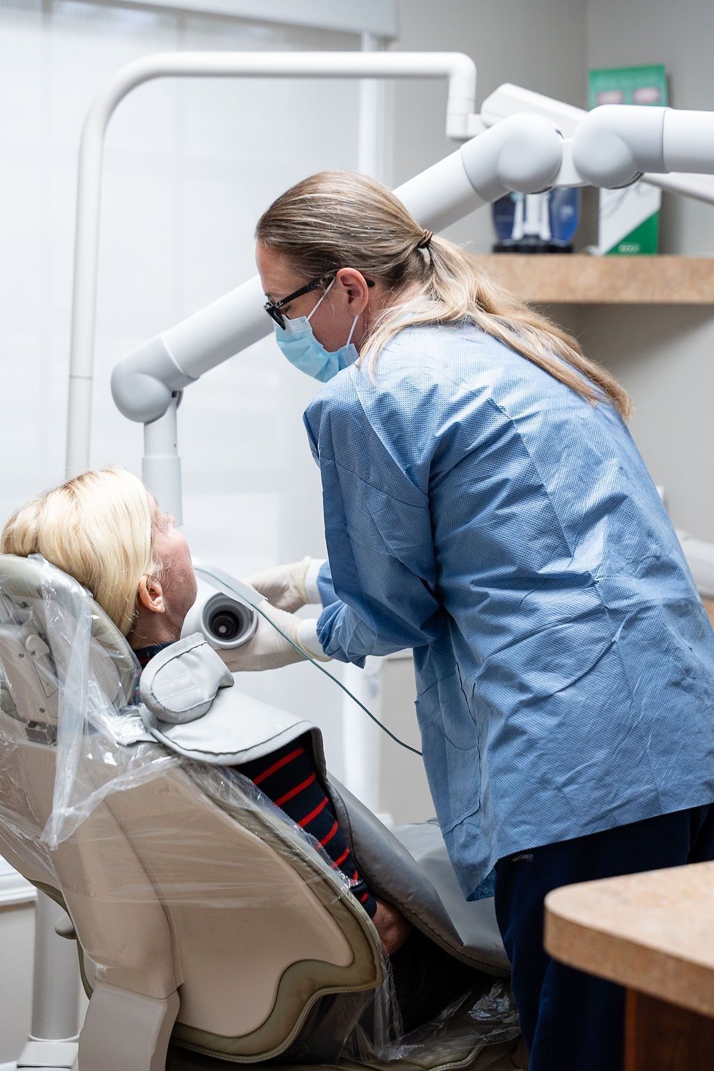 Dentist in blue scrubs treating a patient in a dental chair