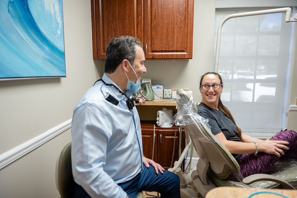 Dentist talking with a smiling patient in a clinic exam room