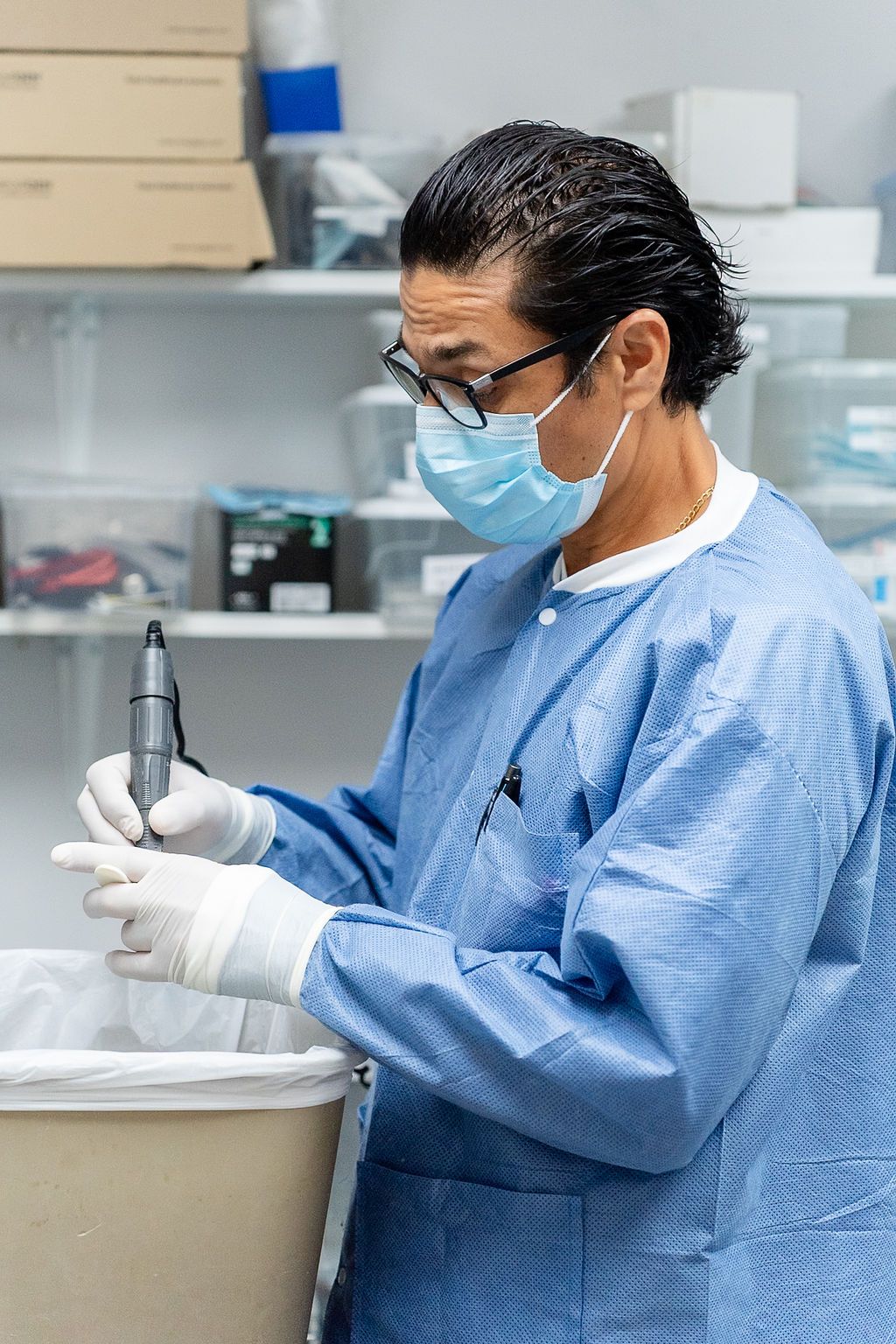 Healthcare worker in blue PPE and gloves preparing a syringe