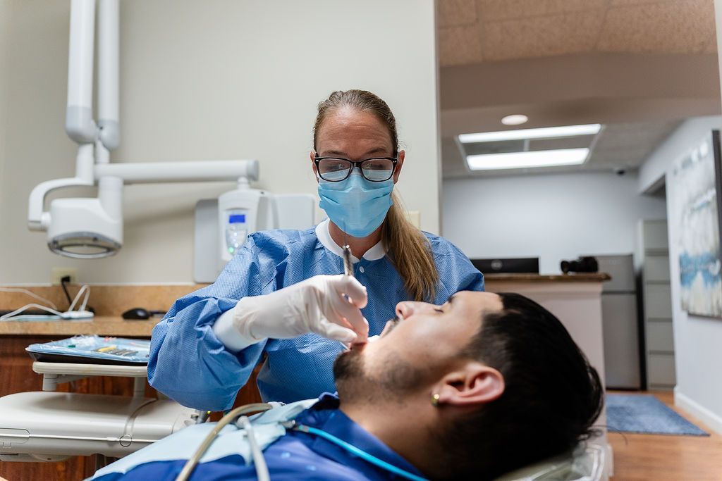 Dentist wearing gloves and mask examining a patient in a dental chair