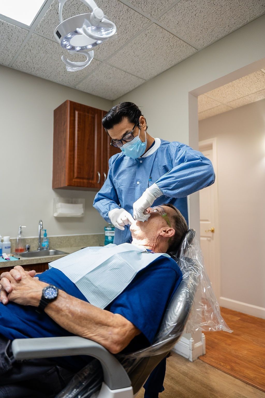 Dentist examining a patient in a reclining chair during a dental procedure