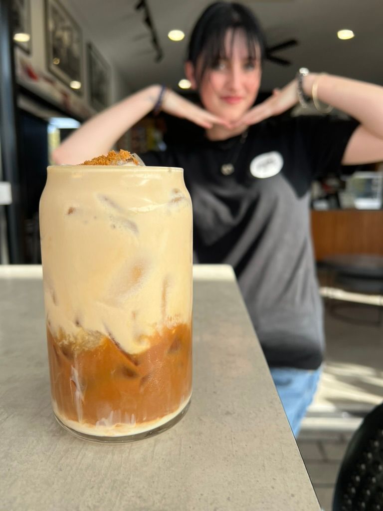 A female staff member posing behind a drink made in the cafe