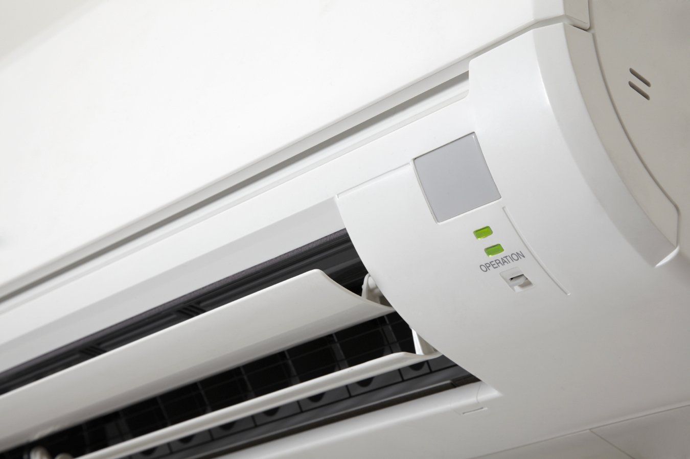 Wall-mounted white air conditioner with vent open and indicator lights lit