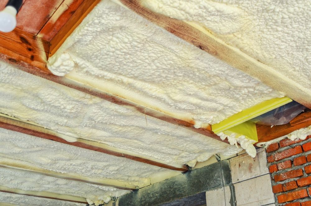 A ceiling with foam insulation and wooden beams.