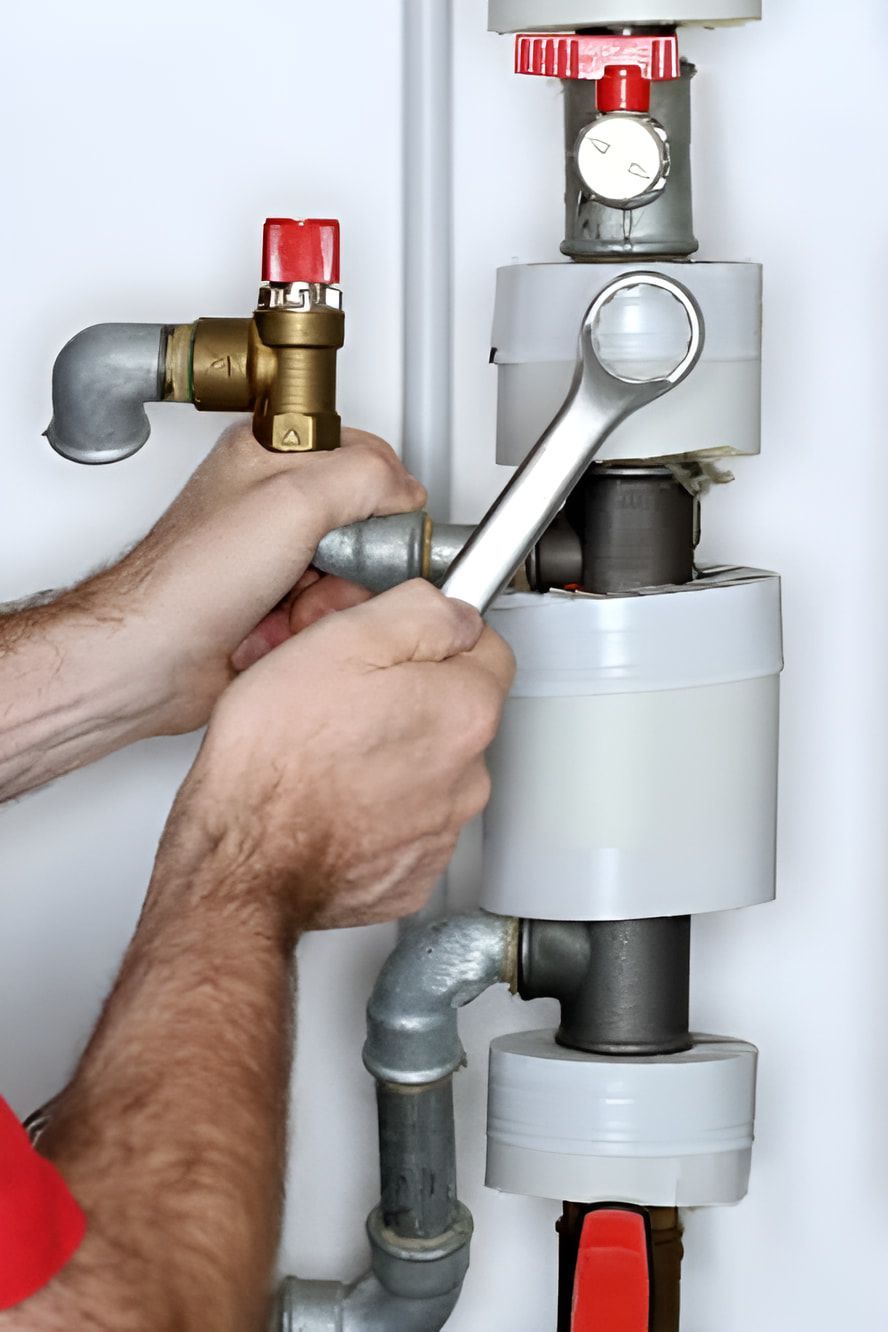 A Man Is Working On A Pipe With A Wrench — ARK Plumbing & Gasfitting In Exeter, NSW