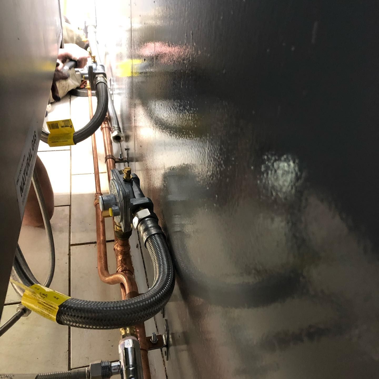 A Close Up Of A Hose Connected To A Gas Valve On A Wall — ARK Plumbing & Gasfitting In Bowral, NSW