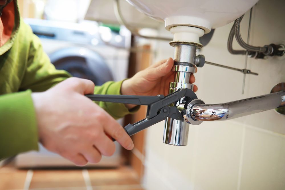 A Person Is Fixing A Sink With A Wrench — ARK Plumbing & Gasfitting In Bundanoon, NSW