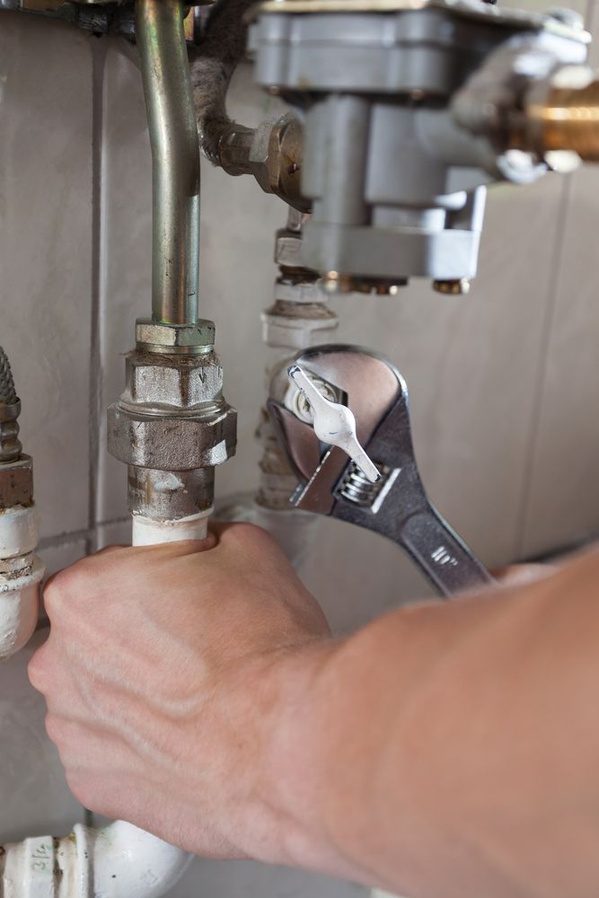A Person Is Fixing A Pipe With A Wrench — ARK Plumbing & Gasfitting In Exeter, NSW