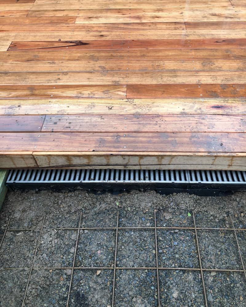 A Wooden Deck With A Metal Drain Underneath It — ARK Plumbing & Gasfitting In Bundanoon, NSW