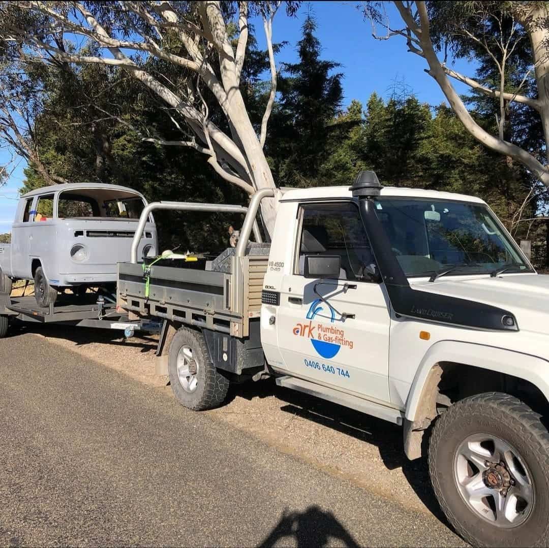 A White Truck With A Trailer Attached To It Is Parked On The Side Of The Road — ARK Plumbing & Gasfitting In Exeter, NSW