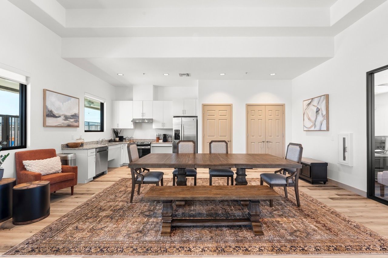 Open-concept kitchen and dining area in a modern apartment with a large wooden table and rug.