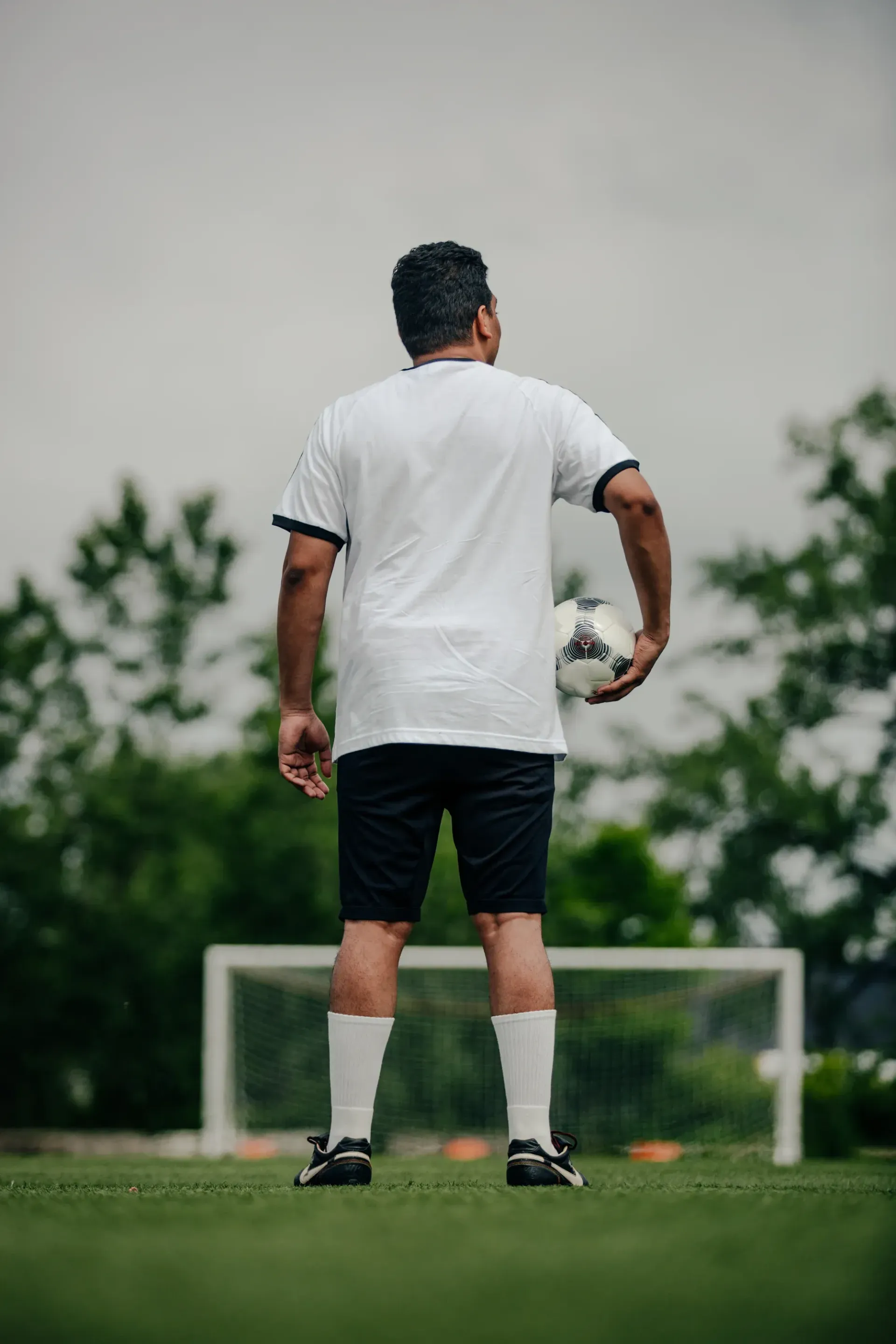 a man standing taking a photo at soccer field while holding ball