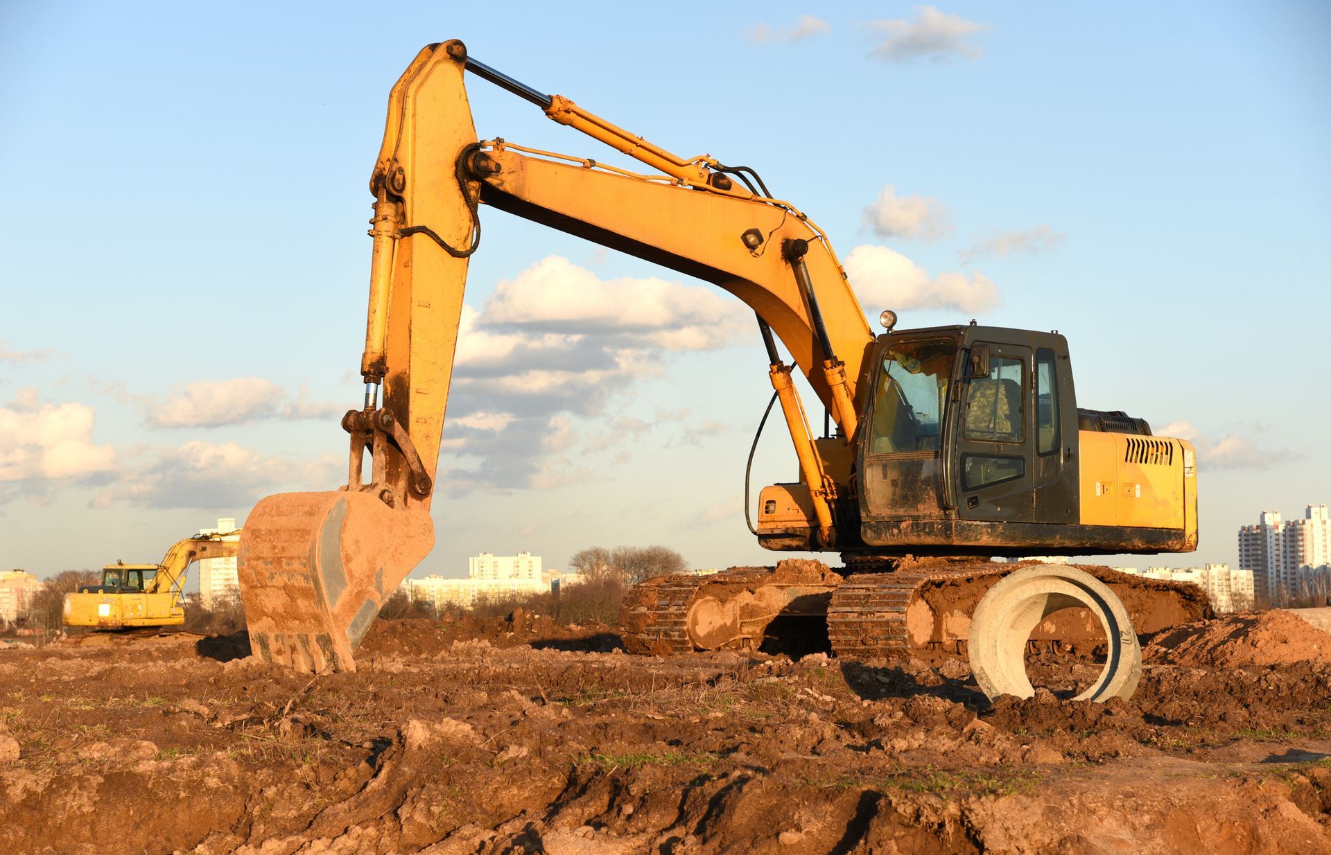 A yellow excavator is moving dirt on a construction site.