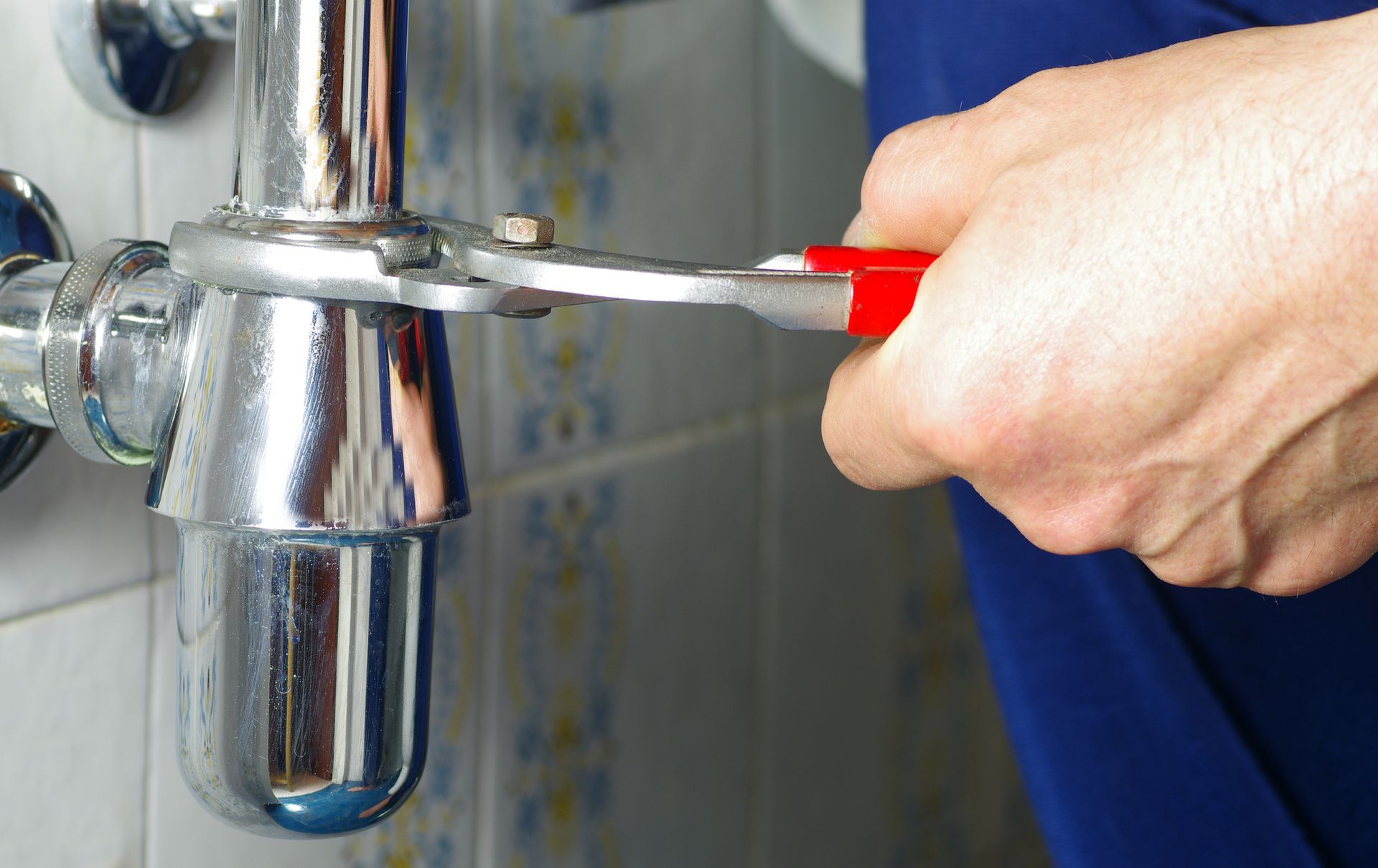 A person is fixing a pipe with a wrench