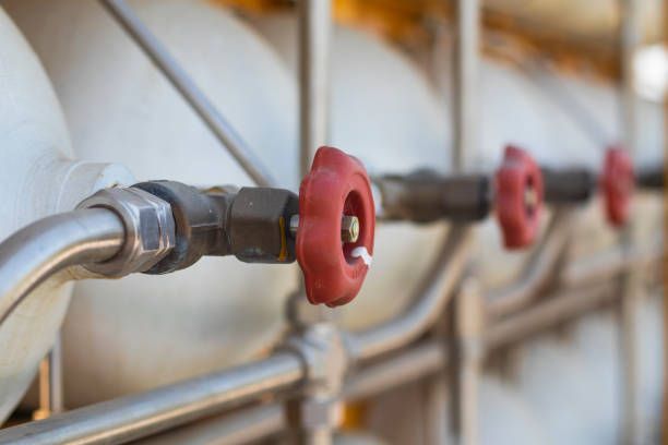 A row of pipes with red valves attached to them.
