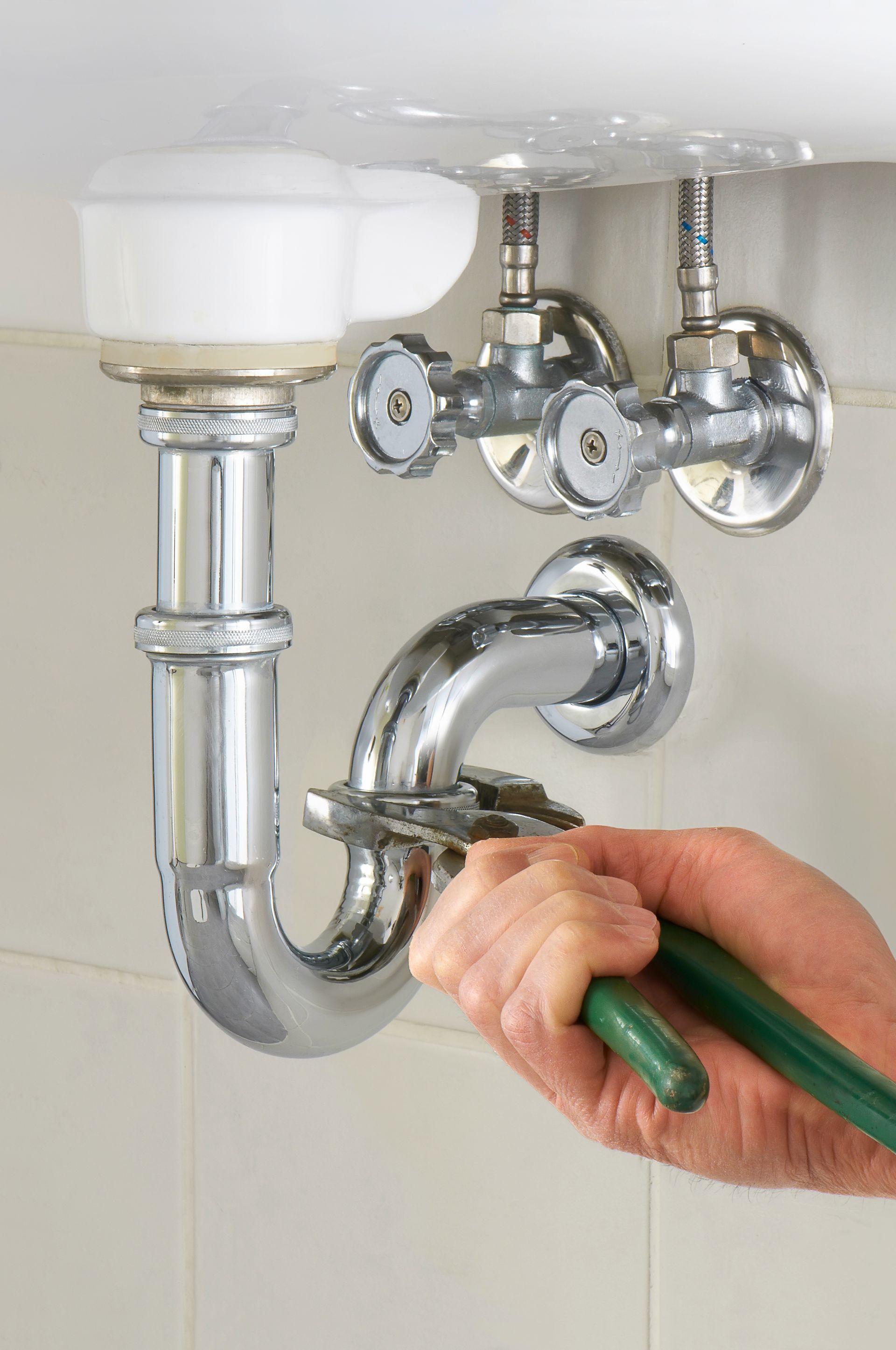 A person is fixing a sink pipe with a wrench