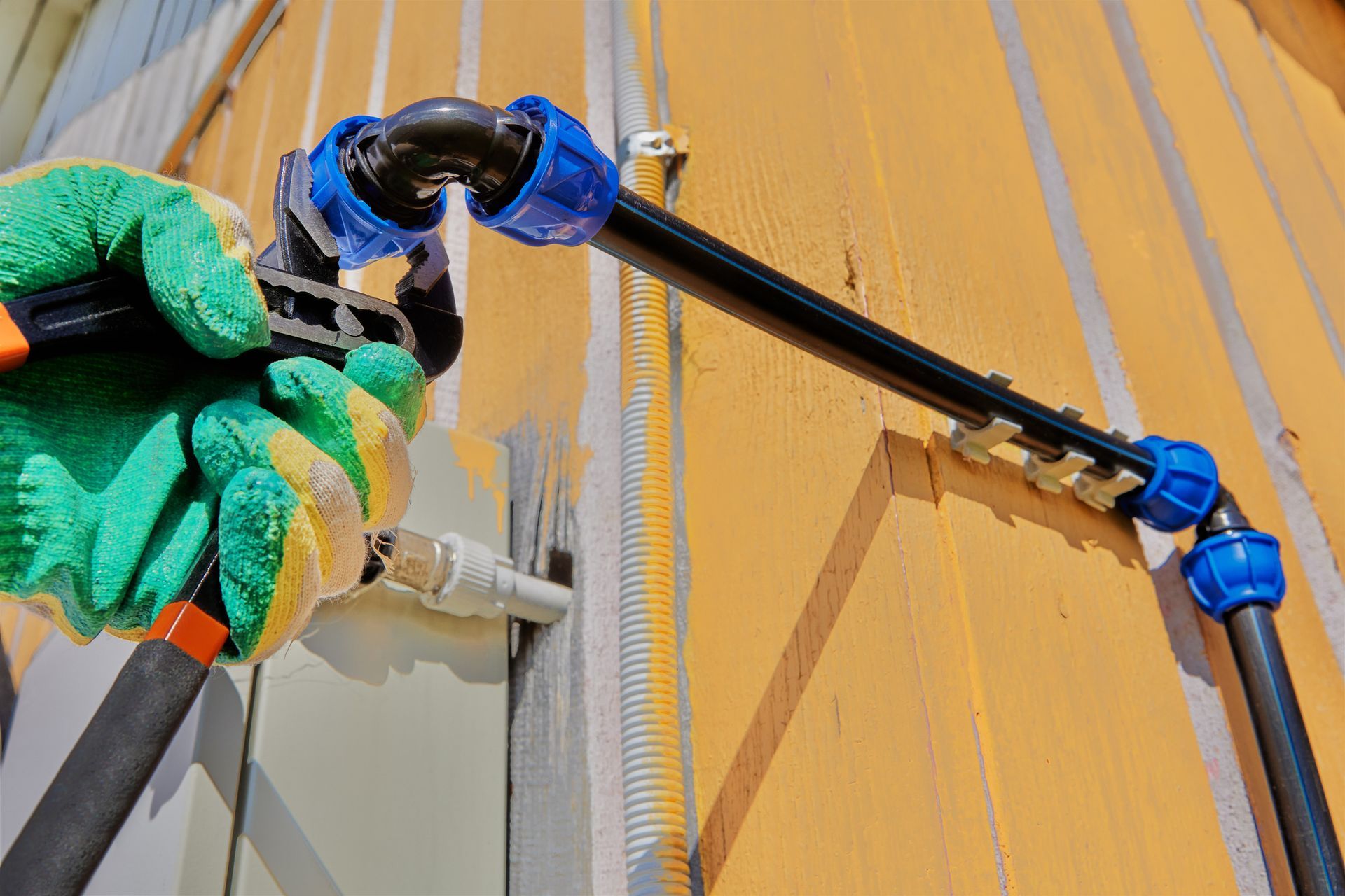 A person is holding a pair of pliers next to a pipe.
