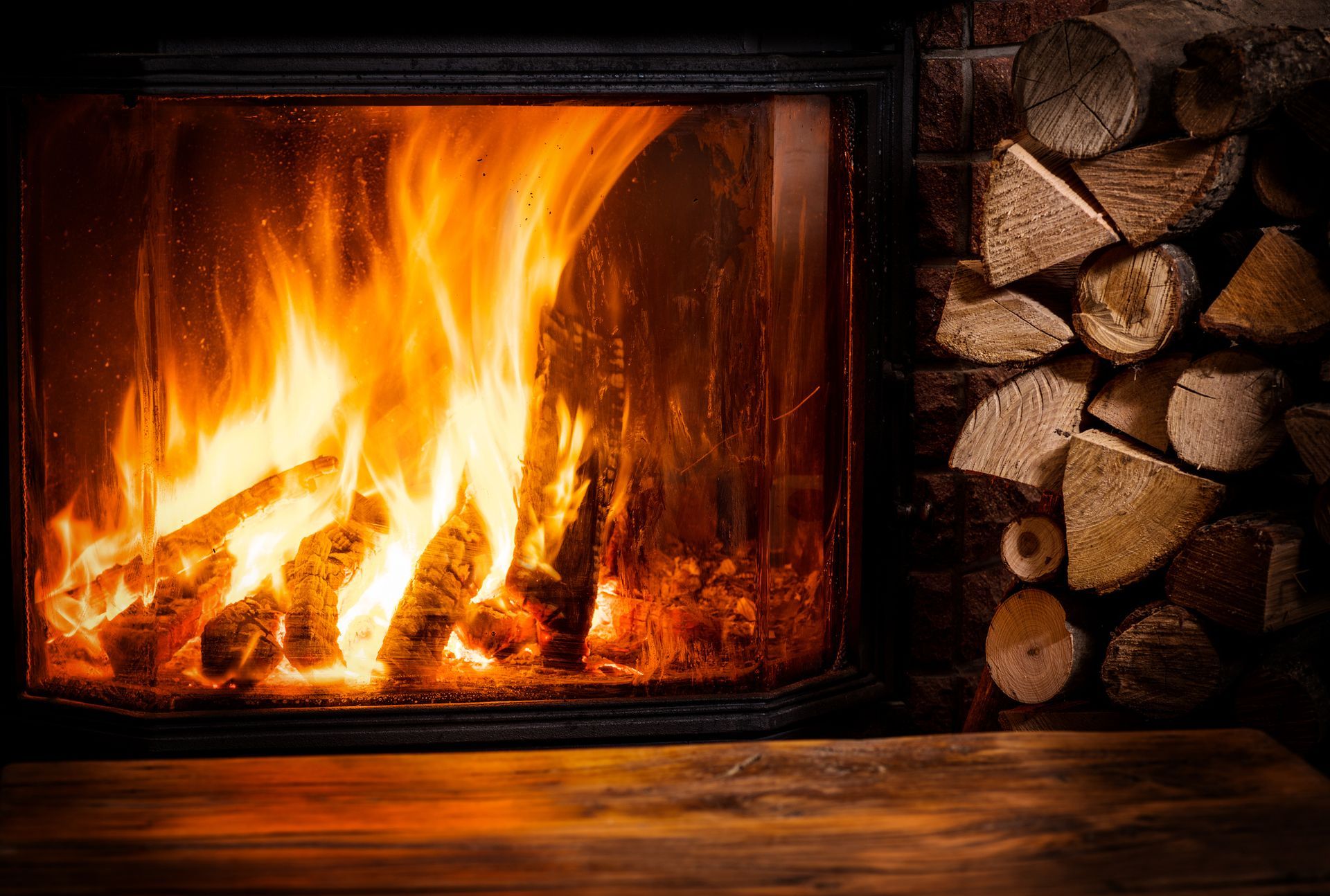 A fireplace with a pile of logs in the background.