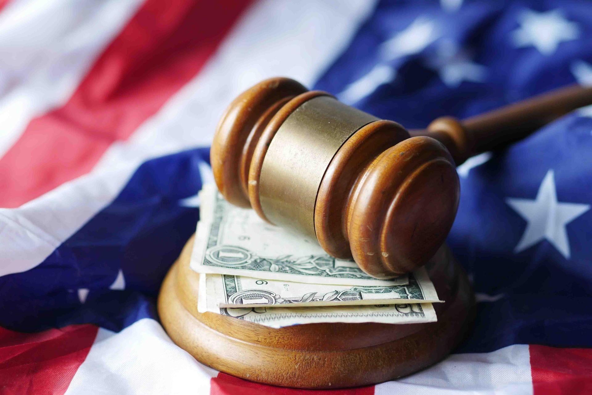 Gavel resting on cash atop a U.S. flag, symbolizing legal fines or financial justice