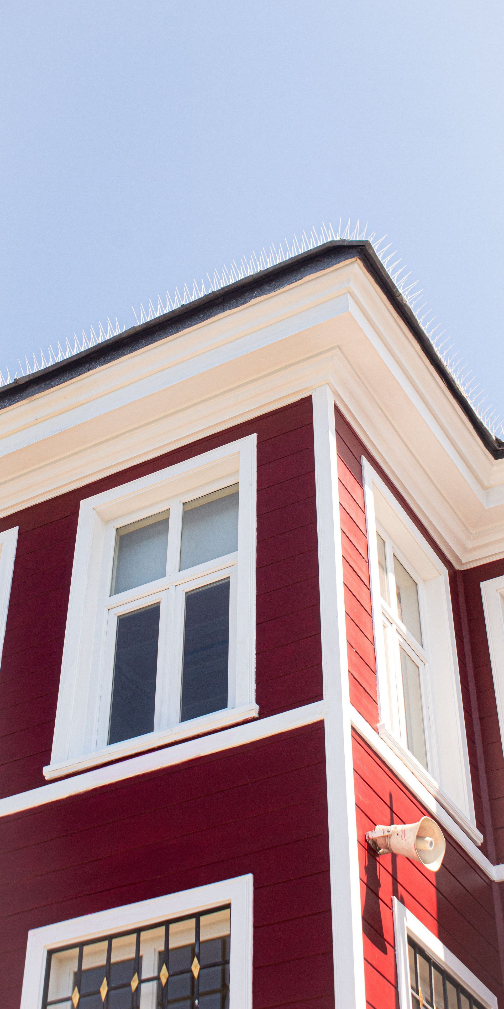 Corner of a red and white building with white-trimmed windows and roofline against a blue sky