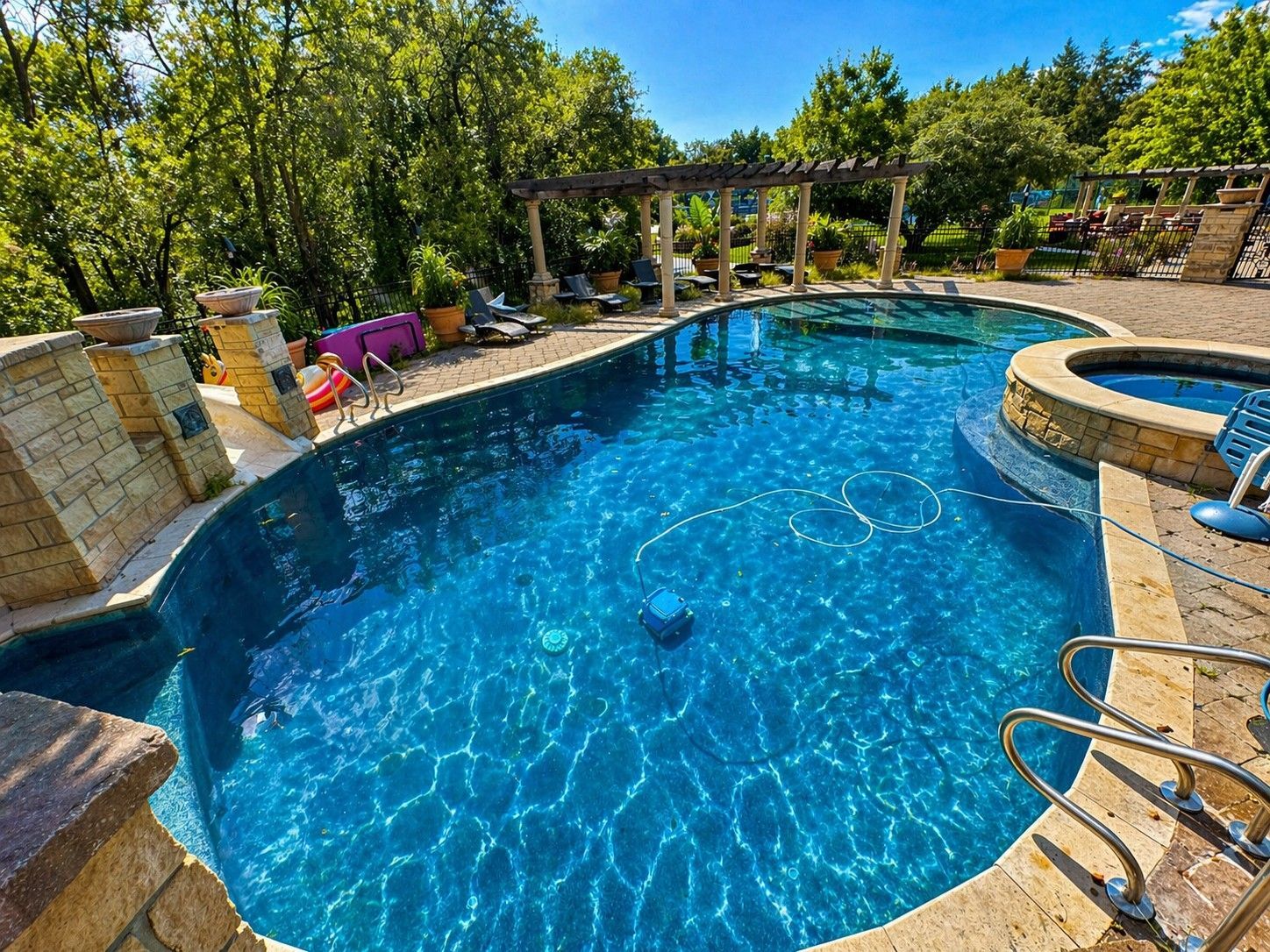 Curvy blue pool surrounded by stone and trees