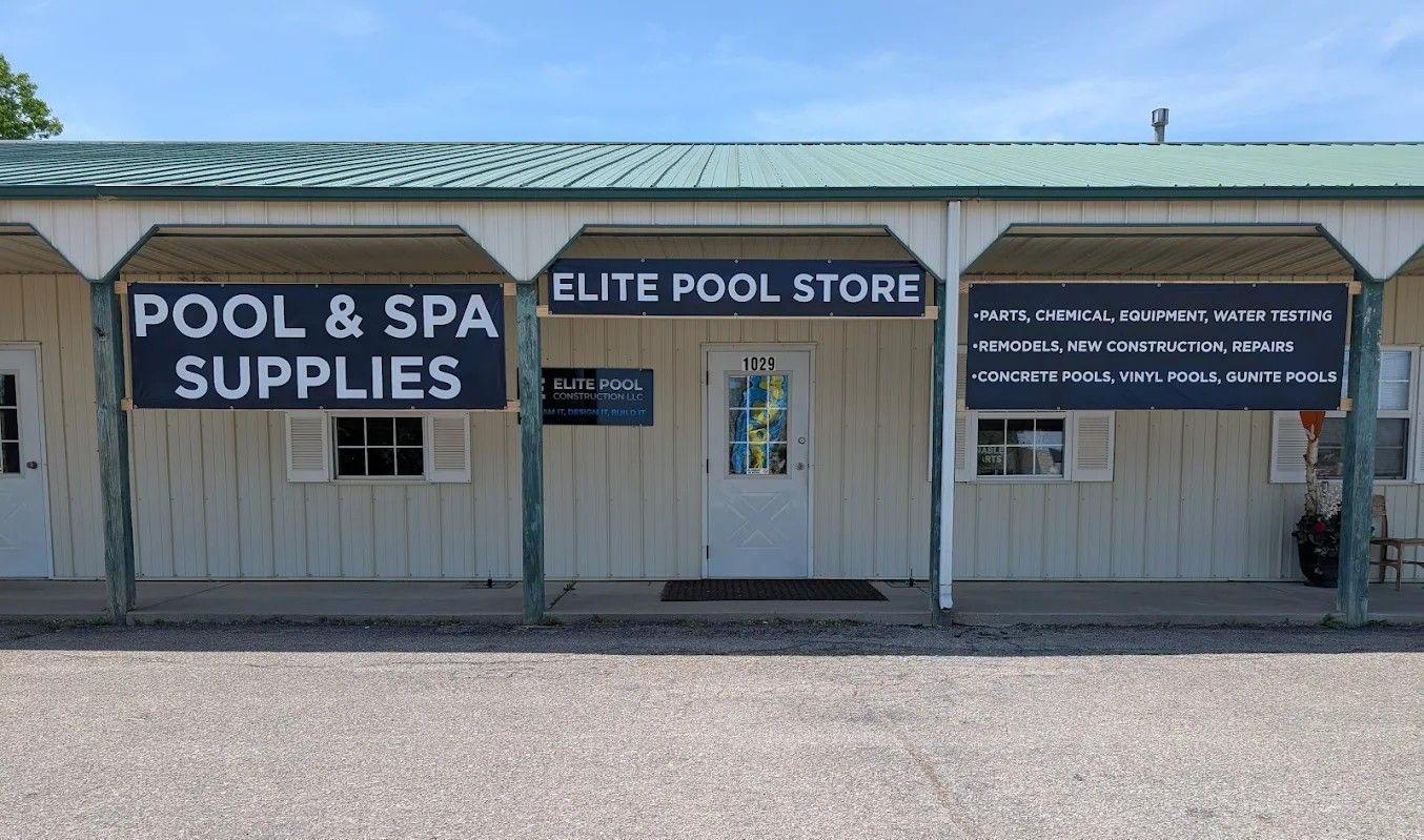 Small storefront for “Elite Pool Store” with pool and spa supply signs under a covered strip mall walkway.
