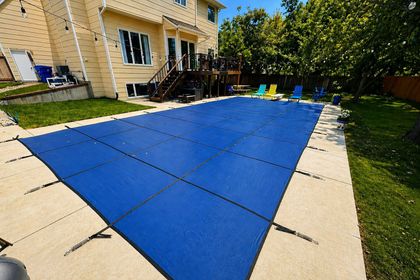 Backyard patio with a pool that has a blue cover on