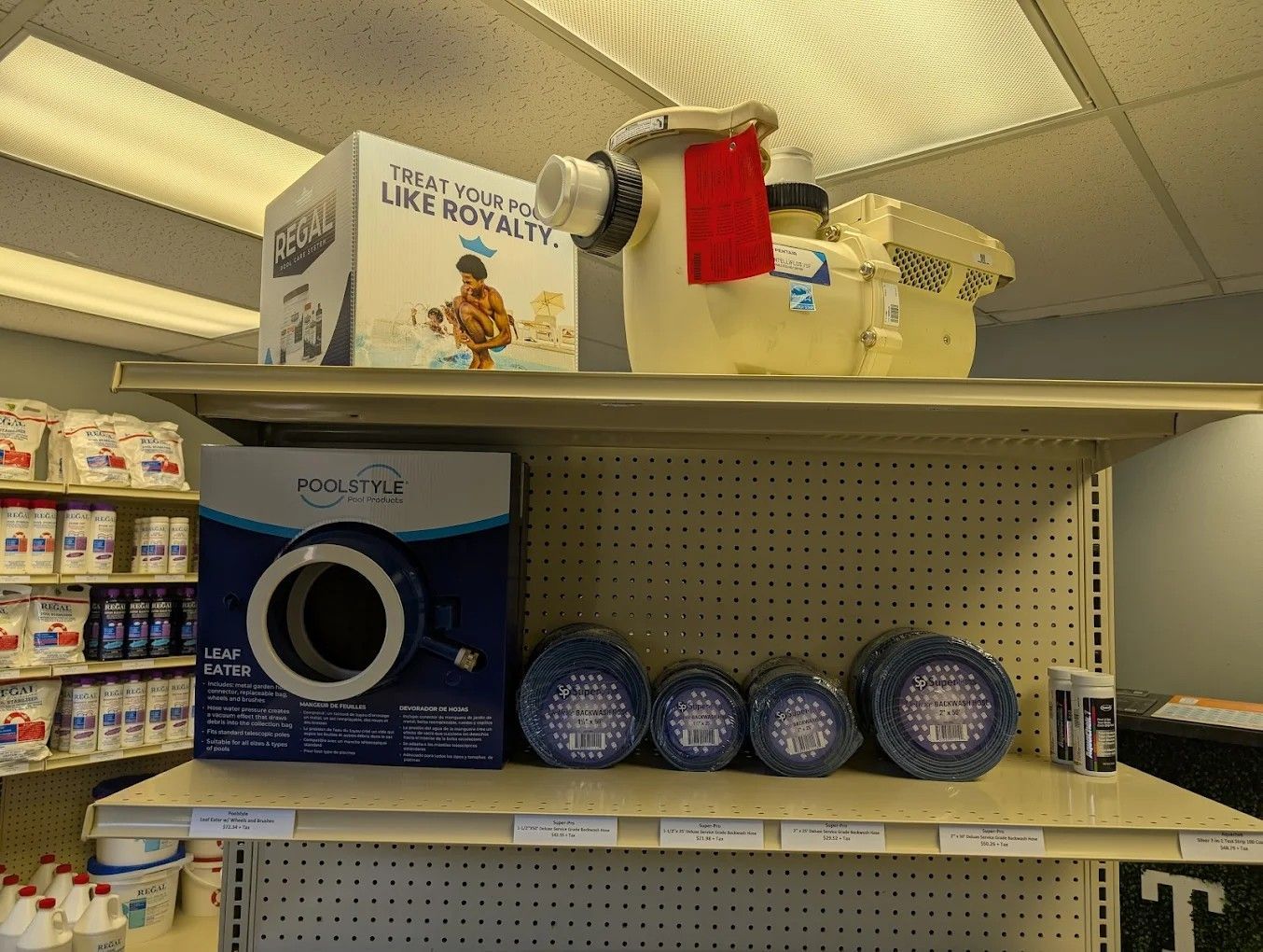 Store shelf with cat litter products, a blue box, round blue plates, and a red cloth hanging above.
