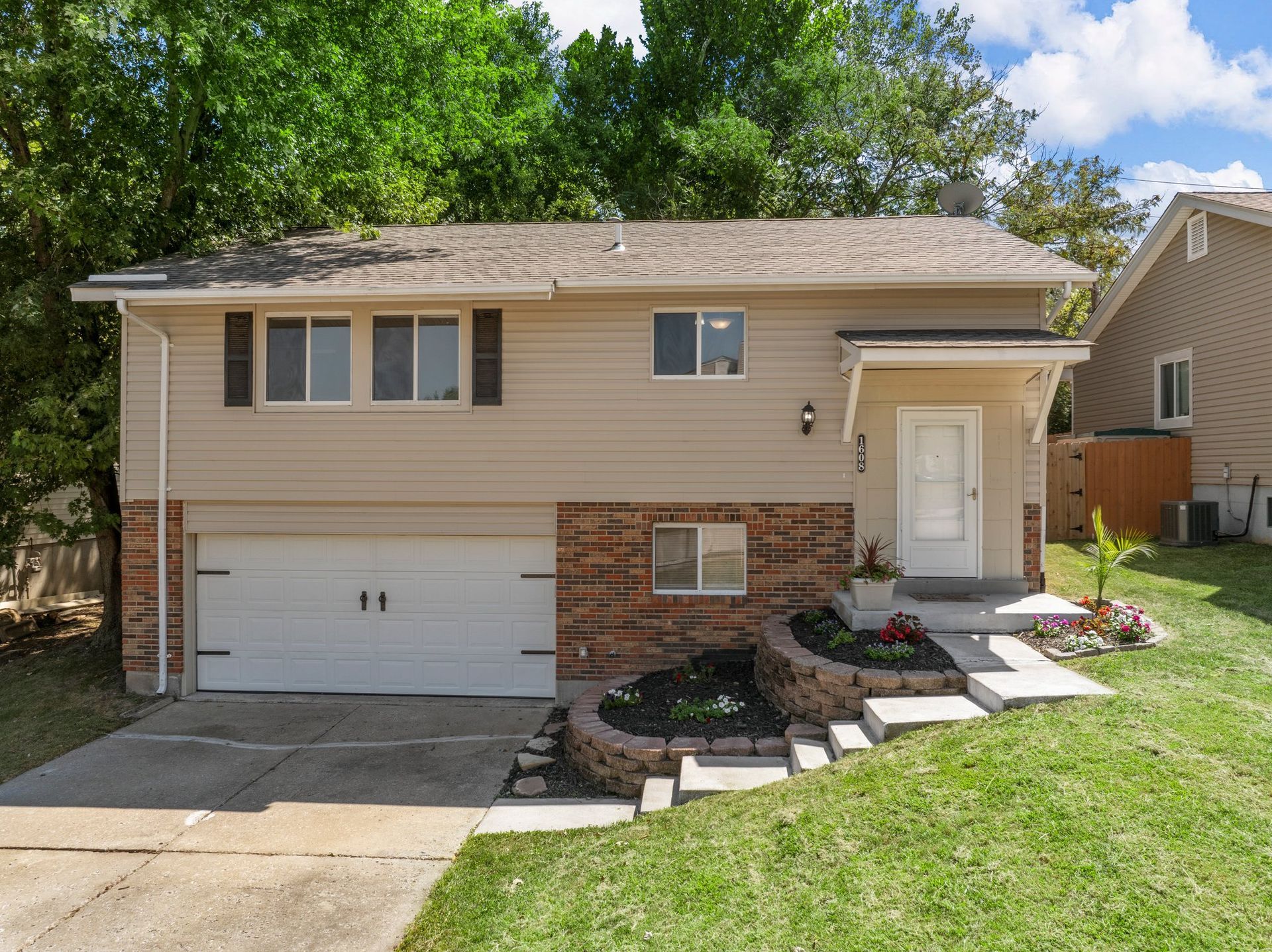 A large house with a white garage door and a lush green yard.