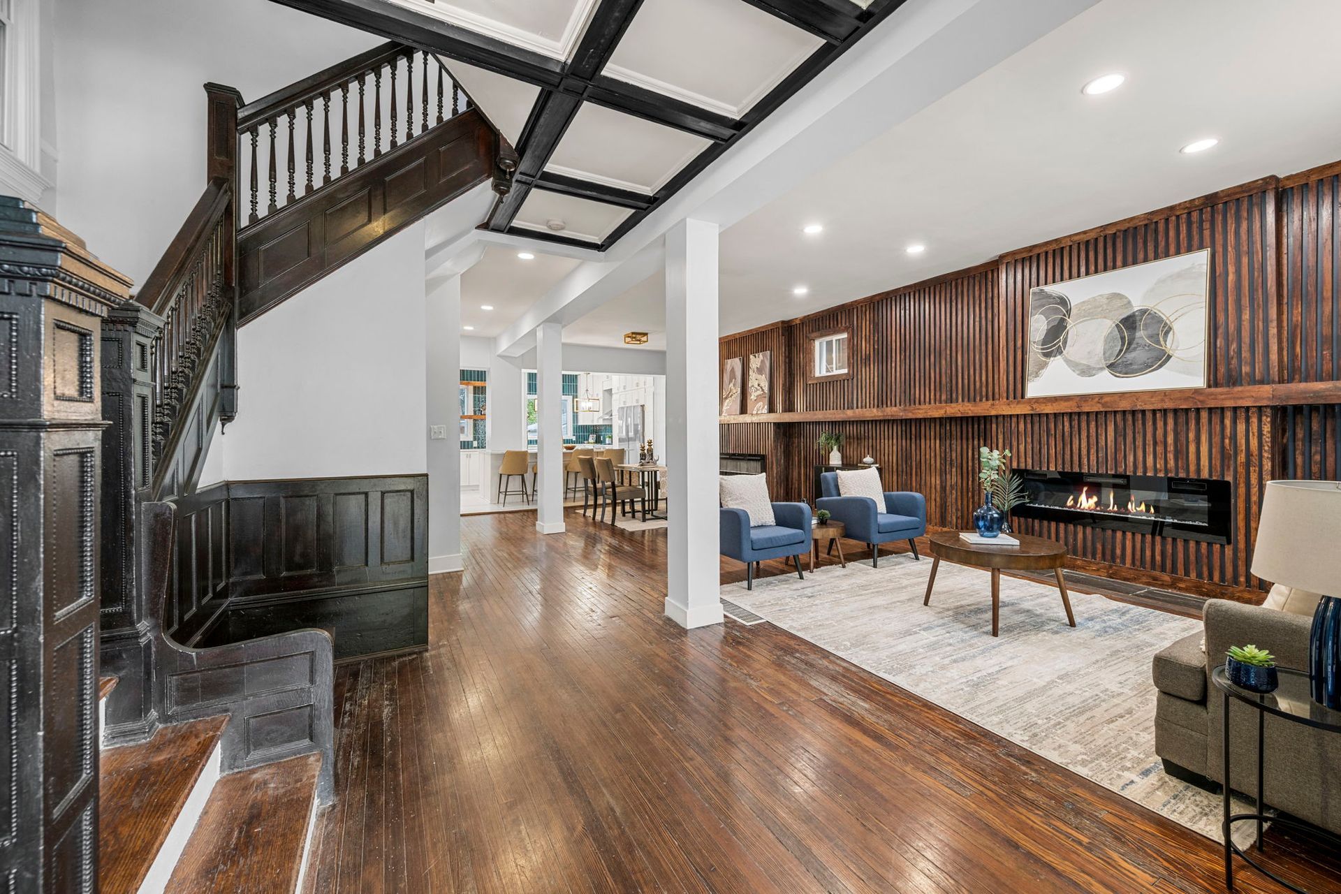 Interior: Dark wood staircase, living room with fireplace and blue armchairs.