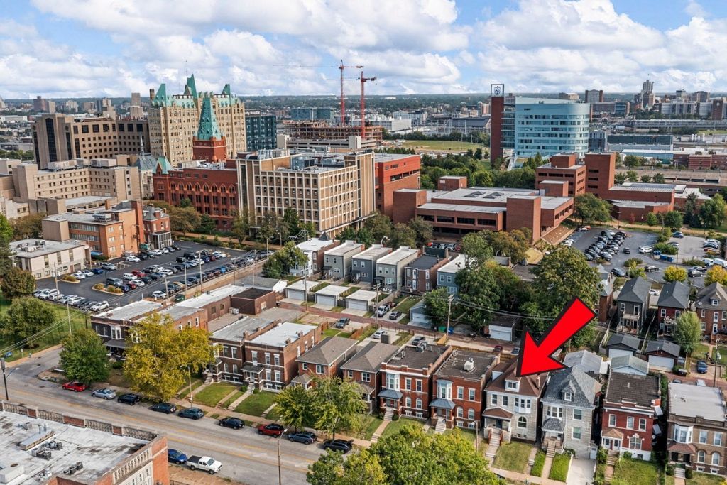 Aerial view of row houses in a city, red arrow points to a specific house.
