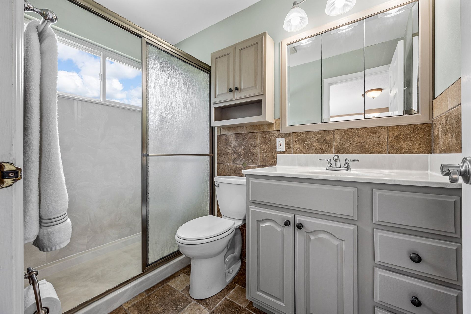 A bathroom with a toilet , sink , and shower.